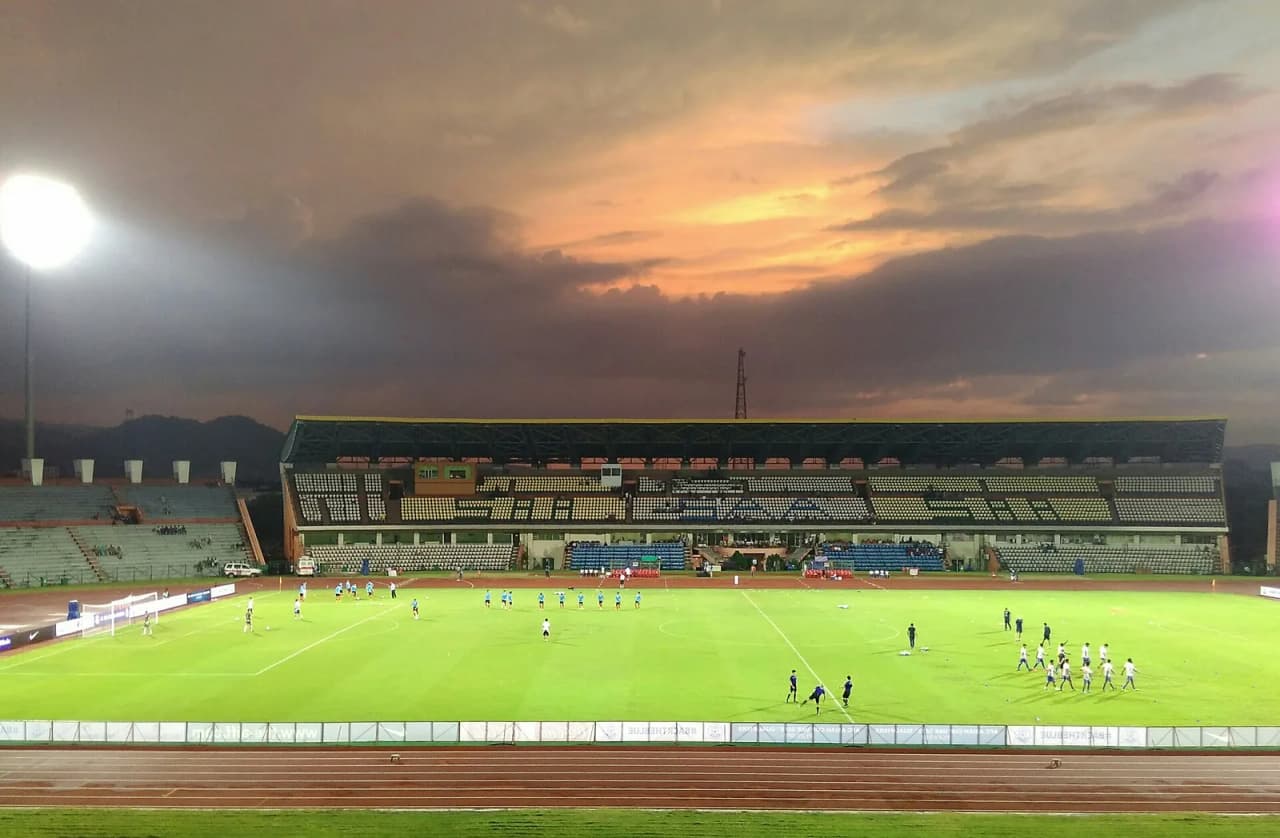 The Main Stand of the Indira Gandhi Athletic Stadium in the background while the players of the Indian National Football team and the Laos National Football team warm-up under the floodlights