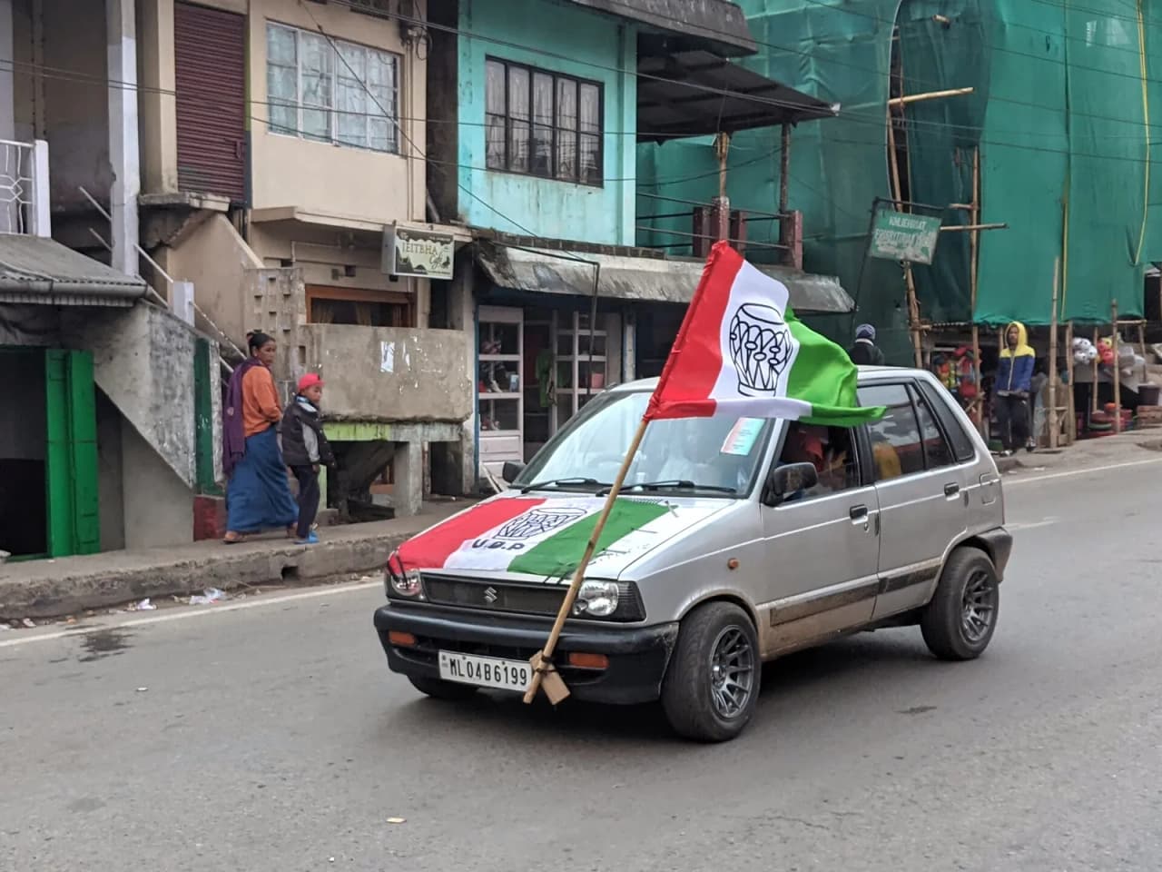 Car with the flag of the United Democratic Party (UDP) both spread across its hood and flying from a pole, showing the owner's support for that party in the 2023 legislative assembly elections in…